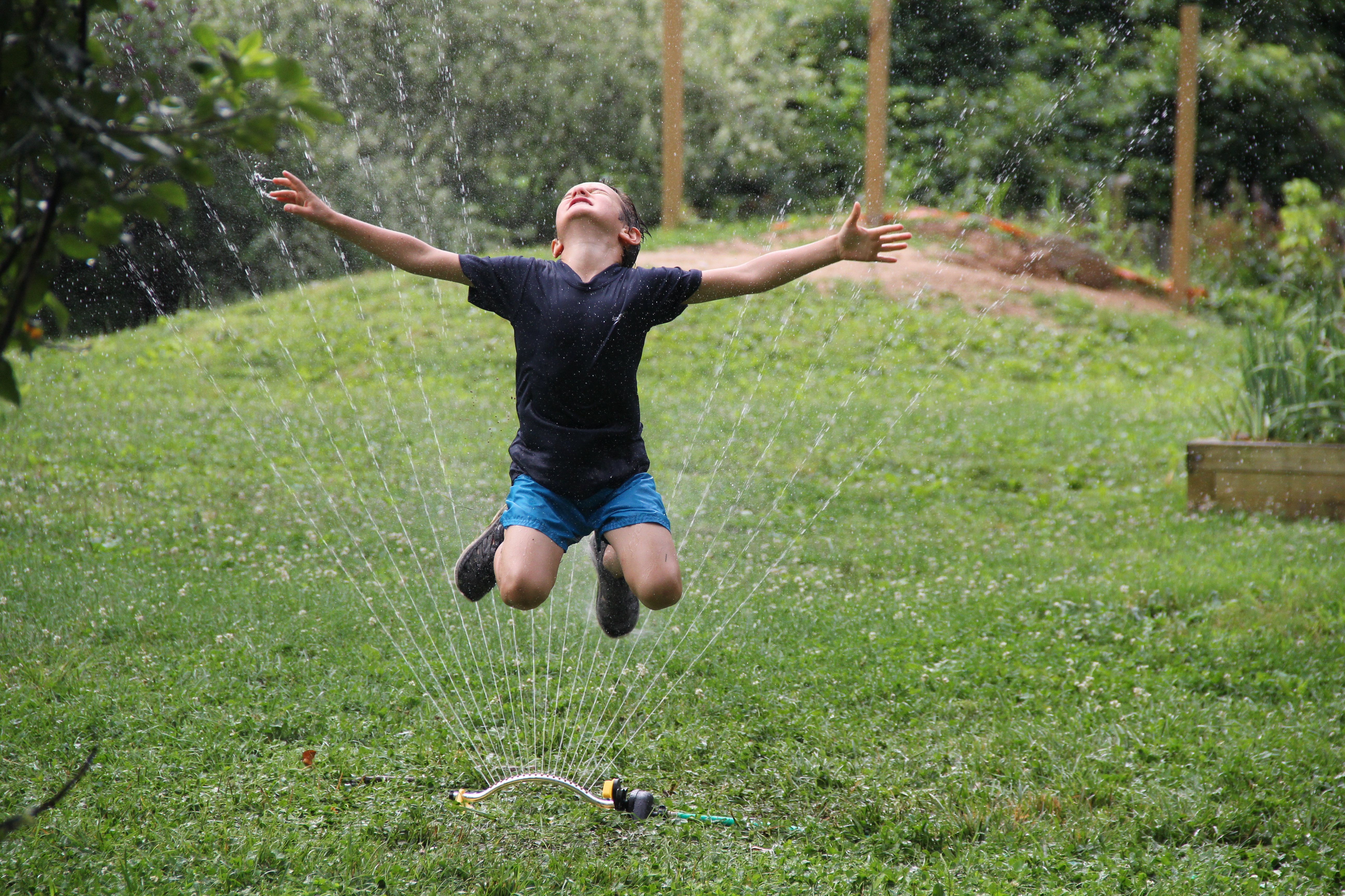 child jumping in a sprinkler