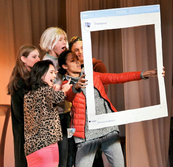 Five kids on stage looking through a frame